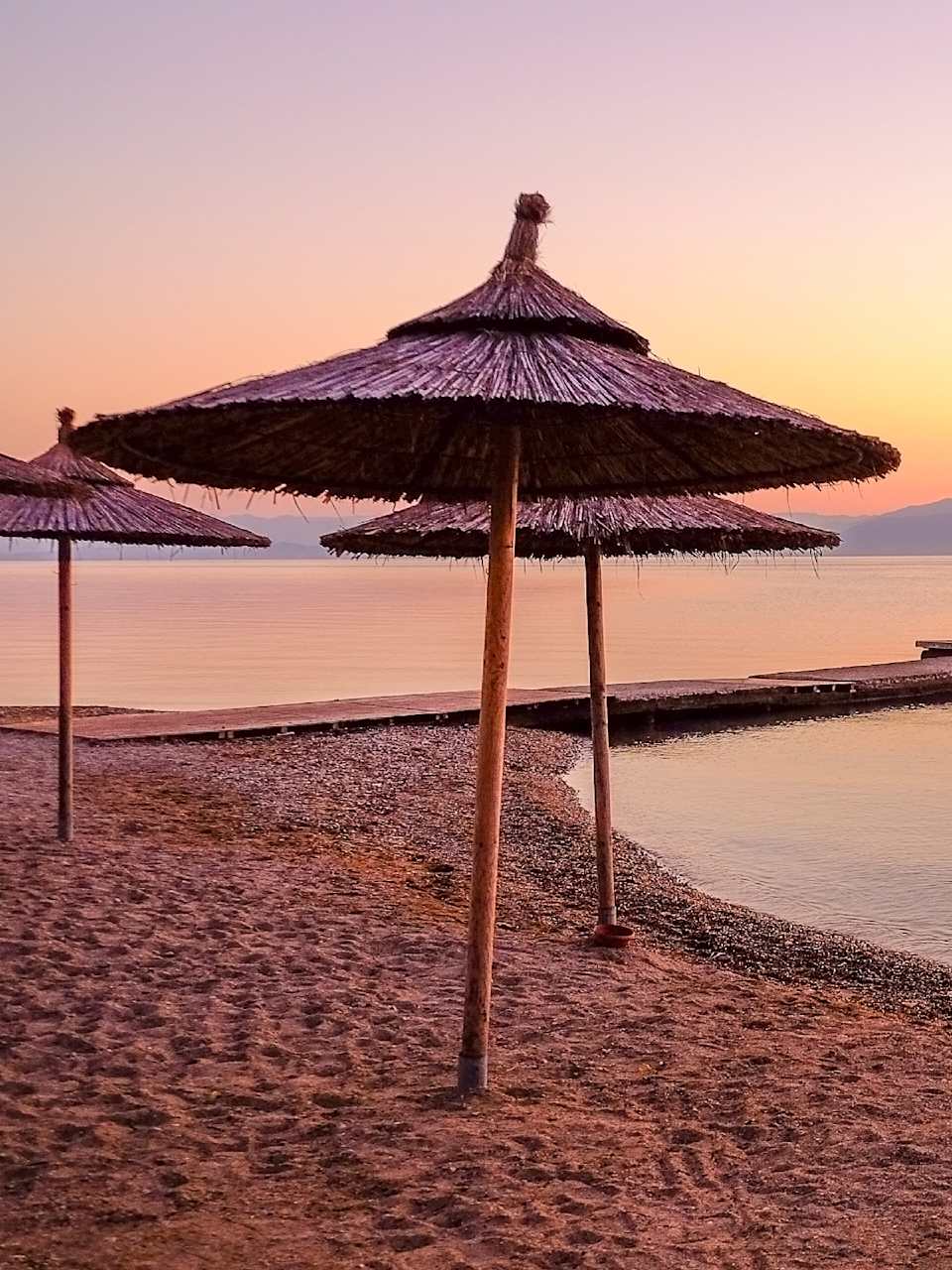 Ein Strand bei Dämmerung mit Strohschirmen